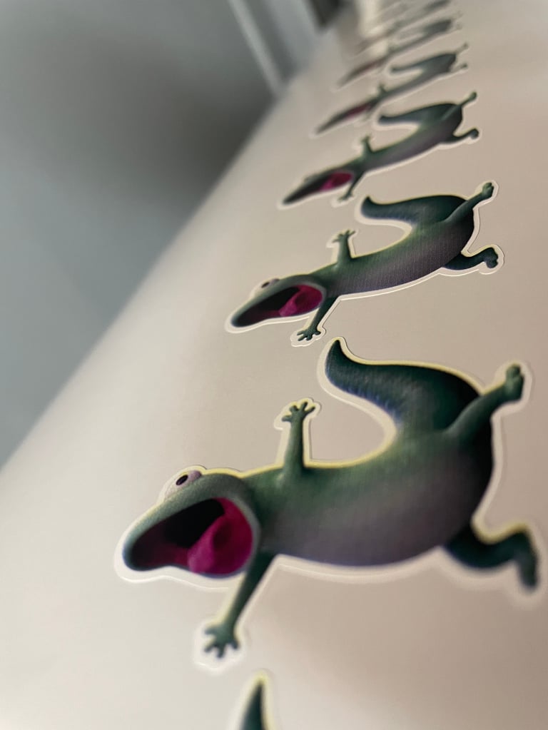 Collection of green lizard stickers arranged diagonally on white surface, showing playful climbing poses with pink mouths